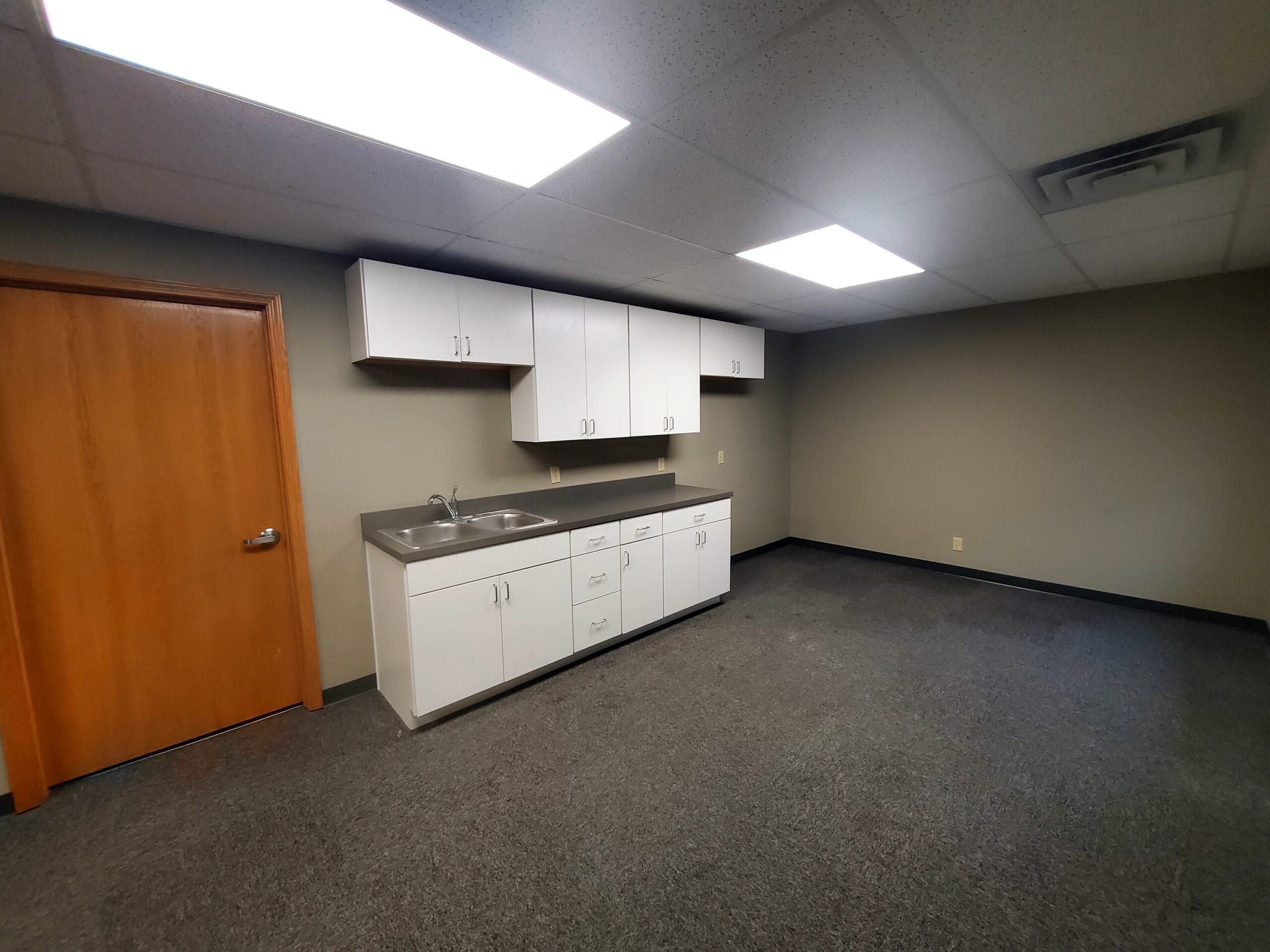 Office kitchenette with white cabinets in leasable commercial space at 304 Legacy Plaza West