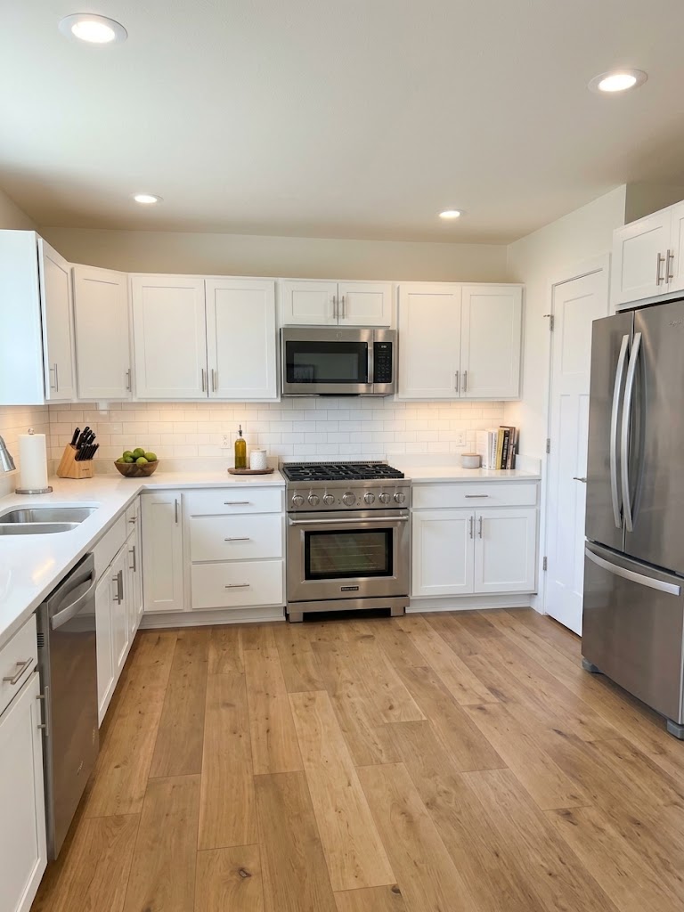 White kitchen with stainless steel appliances and wood floors at 74 Prince William Court, La Porte, Indiana